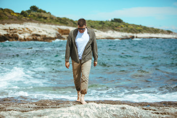 man walking by rocky beach in windy day summer vacation. enjoy sea view