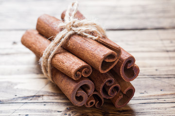 Several cinnamon sticks tied with thread on a wooden background. Copy space. Selective focus.