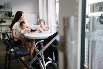 Mother with children drinking hot chocolate and latte at a local coffee shop. They are smiling and having fun.