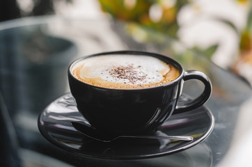 close up modern hot black coffee the cappuccino on dark background with coffee bubble foam pattern and texture in black cup looking and feel so delicious on glasses table in coffee shop.