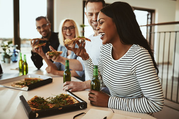 Laughing African American businesswoman having beers and pizza w