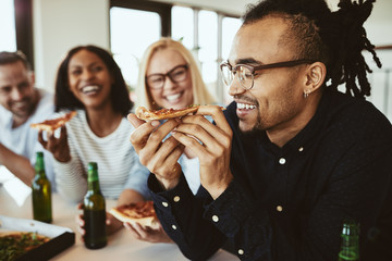 Smiling African American businesswoman having beers and pizza wi