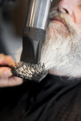 Naklejka premium Hair stylist making styling beard to client in salon