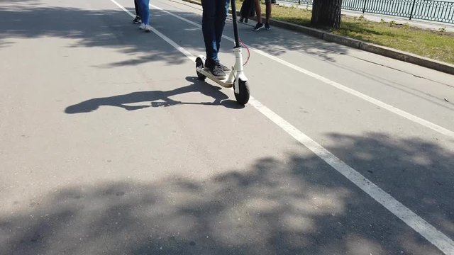Man riding a white electric scooter in the park. People on backgroundscooter3