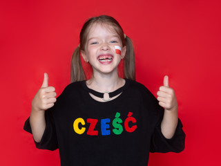 little laughing  girl showing thumbs up , on her sweatshirt the word Hello in Polish, the advertising concept of the Polish school, the study of the Polish language