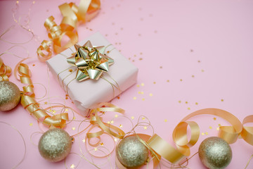 Gift box with golden bow on black background with decoration and sparkles. Festive concept copyspace top horizontal view
