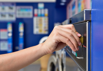 Image of women hand inserting coin into washing machine at self service laundry room