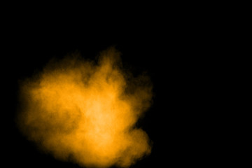 Abstract explosion of orange dust on black background. Freeze motion of orange powder splashing.