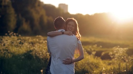 Young man and woman strolling in a meadow at sunset in summer. Romance. Summer love togetherness joy romantic memories forever together concept