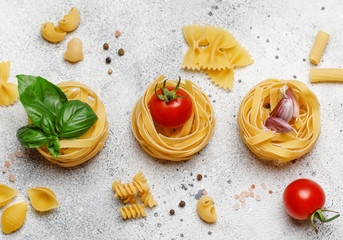 Uncooked pasta on grey stone background. Top view. Raw pasta with ingredients for cooking. Food...