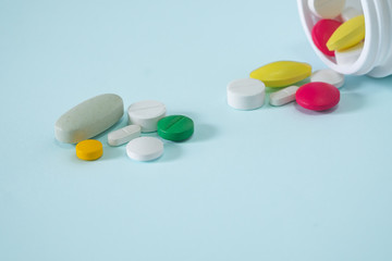 Colorful, assorted pharmaceutical medicine pills poured out of the bottle. many pills and tablets isolated on blue background.
