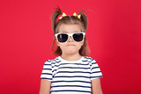 Cute little girl in sunglasses on red background