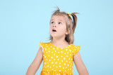 Cute little girl in yellow dress on blue background