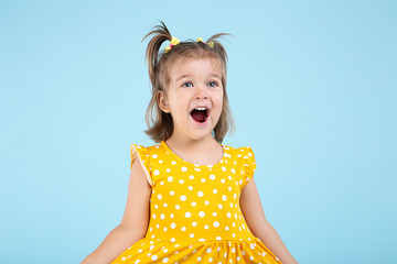 Cute little girl in yellow dress on blue background