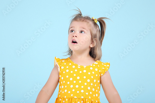 Cute little girl in yellow dress on blue background