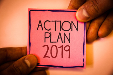 Text sign showing Action Plan 2019. Conceptual photo Challenge Ideas Goals for New Year Motivation to Start Man hold holding pink paper ideas black red letters frame shadow on wall