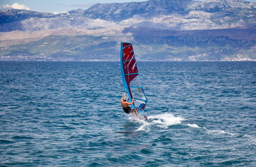 Young windsurfer in the waves in the sea