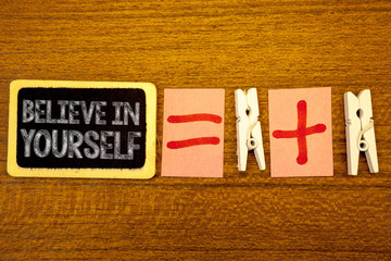 Fototapeta premium Handwriting text Believe In Yourself. Concept meaning Determination Positivity Courage Trust Faith Belief White paper clip laid woody desk black slate some texts equal and plus mark