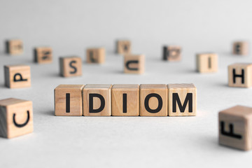 idiom - word from wooden blocks with letters, mode of expression concept, random letters around,...