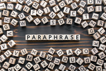 paraphrase - word from wooden blocks with letters, rewrite retelling using other paraphrase words concept, random letters around, top view on wooden background