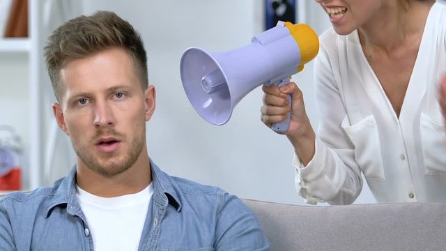 Annoyed female shouting in megaphone on husband, relationship difficulties