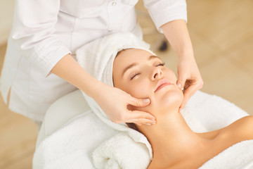 Obraz na płótnie Canvas Beautician makes facial massage to the girl