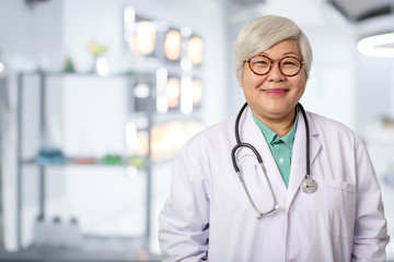 Senior Asian doctor woman with smiling  face on the background of the modern hospital