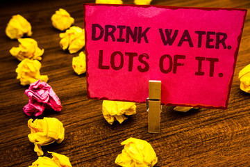 Fototapeta premium Conceptual hand writing showing Drink Water. Lots Of It. Business photo showcasing drinking liquids to keep our body in great status Paperclip retrain pink card with letters wooden floor hunch