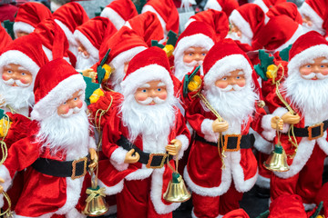 A lot of Santa Clauses standing on the shelf of the souvenir shop.