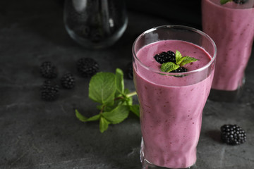 Glass of tasty blackberry smoothie on grey table. Space for text
