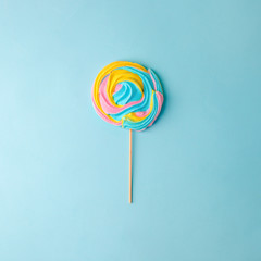 Colorful unicorn rainbow color meringue lollipop candy on pale on blue background. Flat lay. Summer...