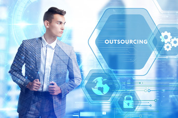 The concept of business, technology, the Internet and the network. A young entrepreneur working on a virtual screen of the future and sees the inscription: Outsourcing