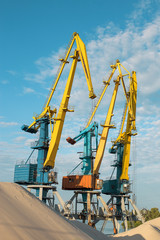Cranes near the sand against a blue sky. Industrial landscape, industrial zone.