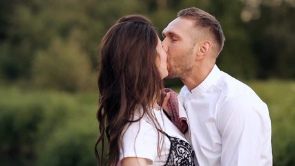 A young couple walks at sunset on a summer day, a girl with a plaid