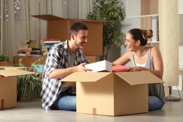 Fototapeta na wymiar Happy couple unboxing belongings moving house looking each other