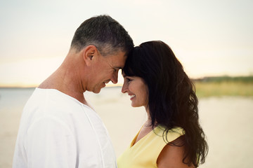 Fototapeta premium Happy mature couple spending time together on sea beach at sunset