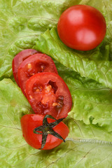 Ripe whole tomatoes and cut into slices on fresh lettuce leaves.