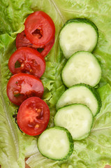 Cucumber and tomato sliced on fresh lettuce leaves.