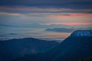 Fototapeta premium Red light before dawn shines on the valley as seen from the mountain top. 