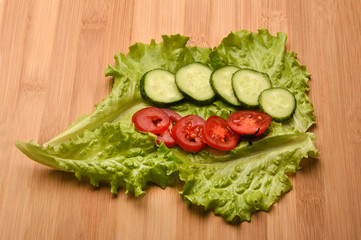 Cucumber and tomato sliced on fresh lettuce leaves.