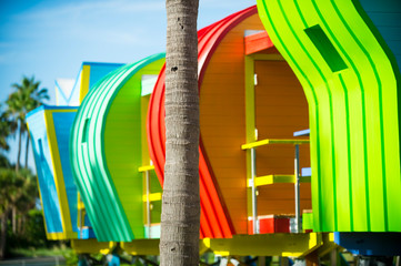 Bright scenic view of colorful new lifeguard towers standing in a row with the shadows of palm trees in South Beach, Miami, Florida, USA