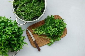 Chopped fresh green parsley and dill or fennel on cutting boar on gray wooden table. Top view. Copy space. Harvesting concept