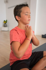 Fototapeta na wymiar Niño con los ojos cerrados meditando y preparándose para yoga