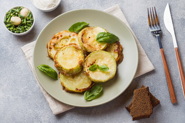 Slices of fried zucchini in batter with garlic and Basil on a plate.