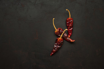 Peppercorns of red hot chilli peppers on dark wooden background. Top view. Copy space. Healthy food concept