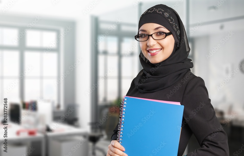 Wall mural beautiful young muslim woman with notebooks on background