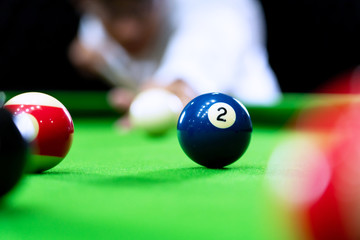 Man's hand and Cue arm playing snooker game or preparing aiming to shoot pool balls on a green billiard table.
