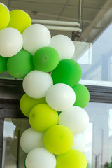 Multi-colored balloons adorn the entrance to the store hall. Conceptual design of inflatable color balls in corporate yellow, green and white colors as a festive background