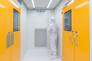 A scientist in sterile coverall gown using Cleaning tool for cleaning laboratory. Cleanroom facility.