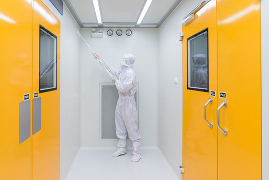 A scientist in sterile coverall gown using Cleaning tool for cleaning laboratory. Cleanroom facility.